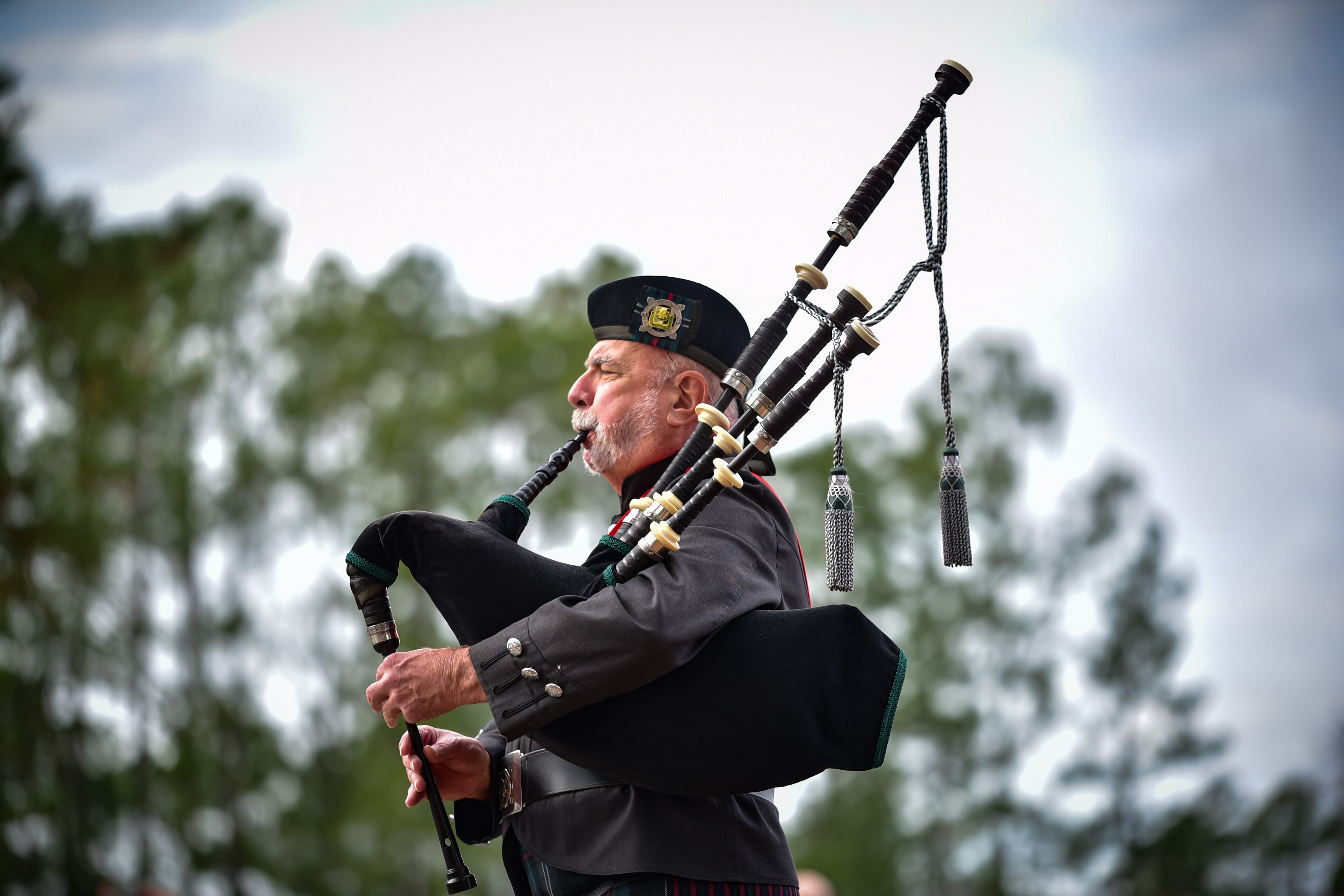 A man playing bagpipes in traditional Scottish attire