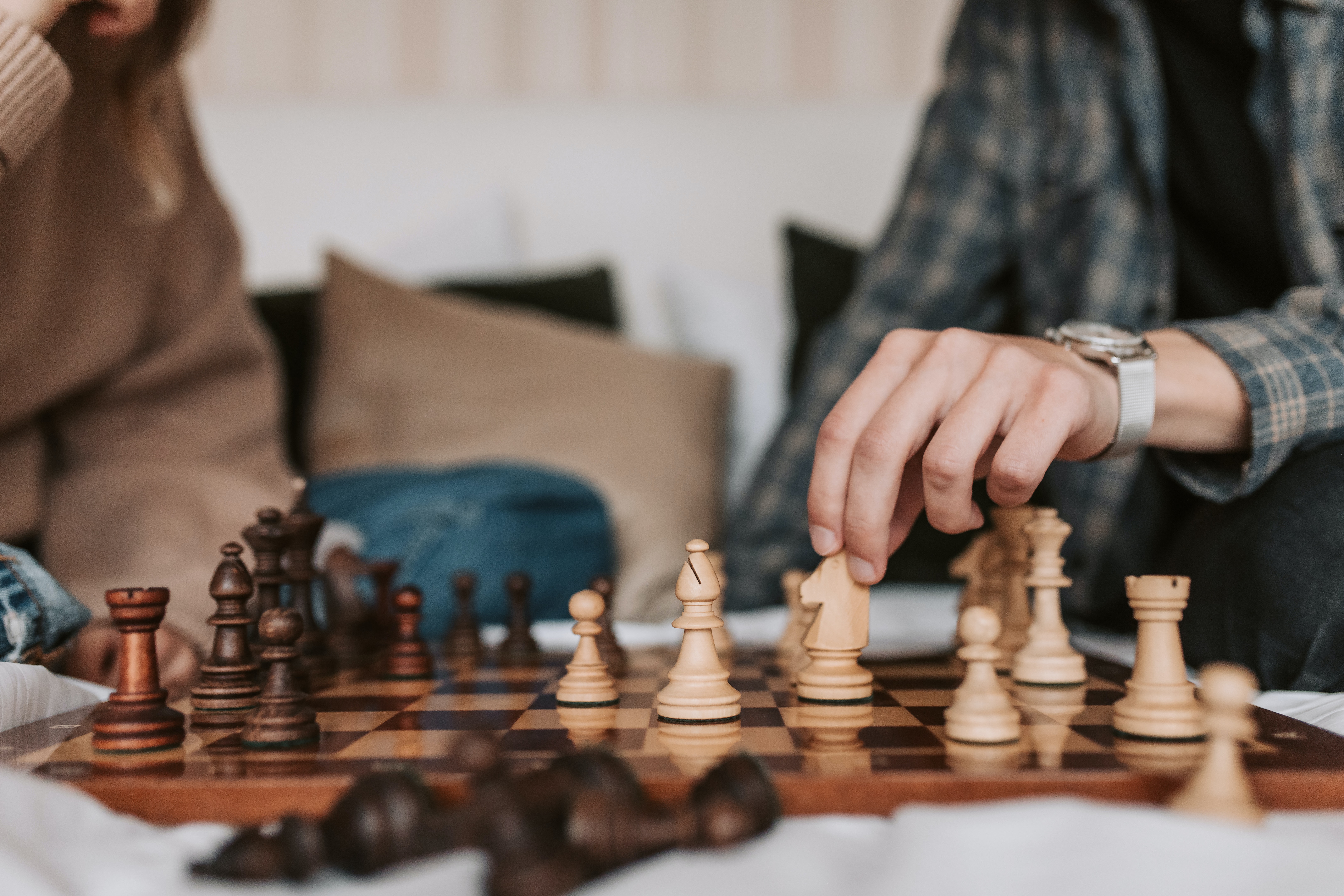 Two people playing a game of chess on a fine wooden board