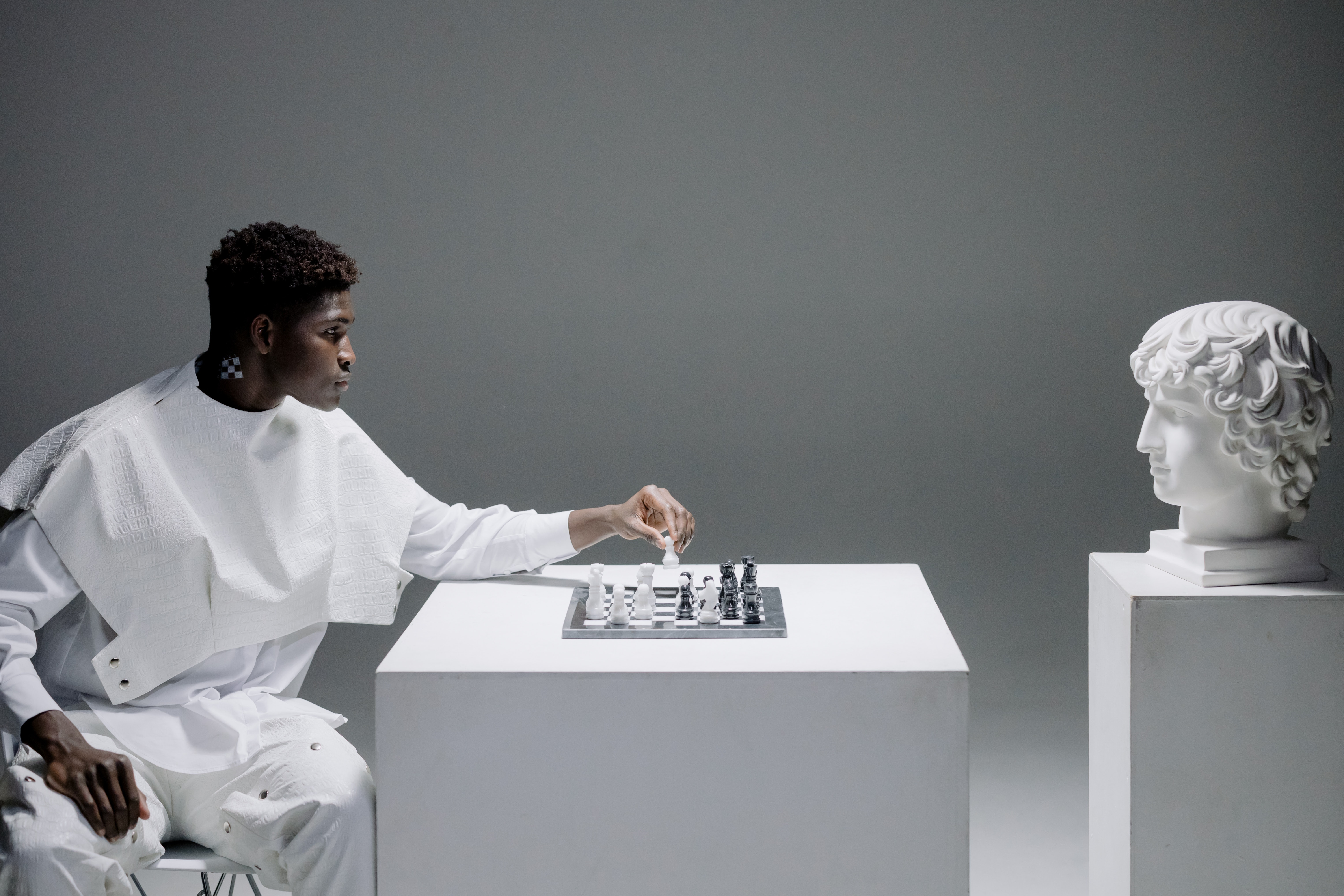 A man playing chess against a bust statue