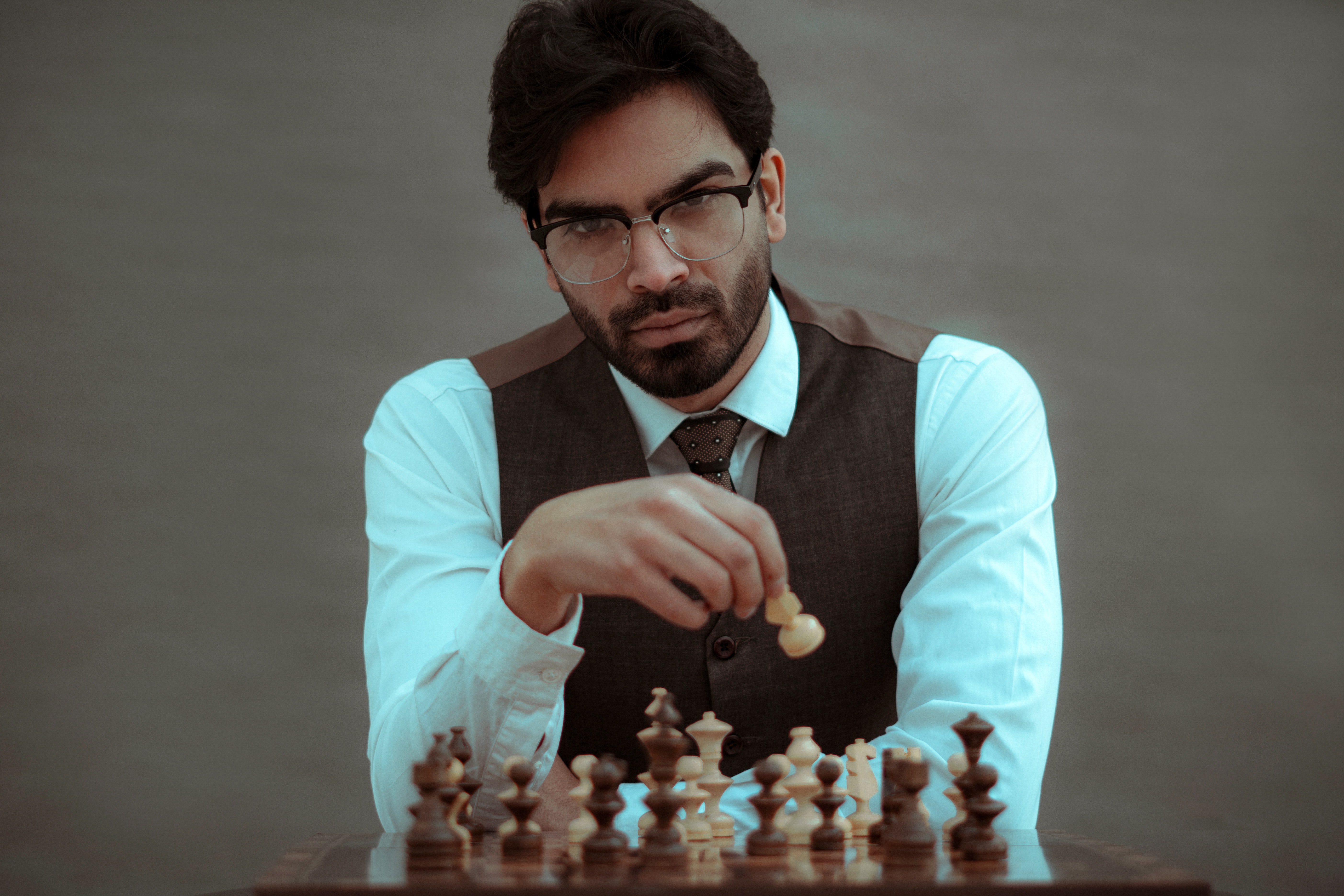 A man sitting at a chess board holding one of the pieces