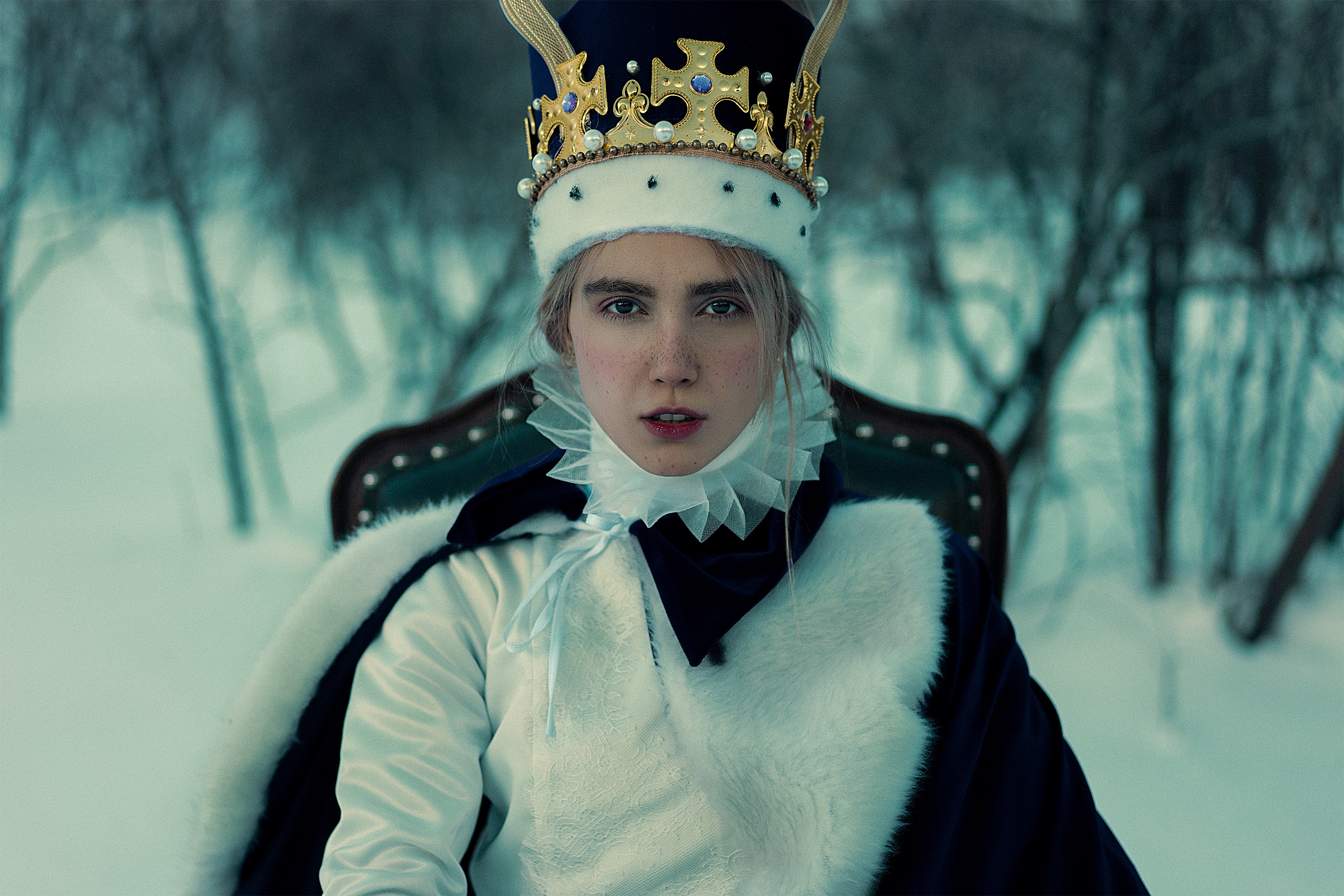 A woman dressed as a queen with a crown in a snowy setting